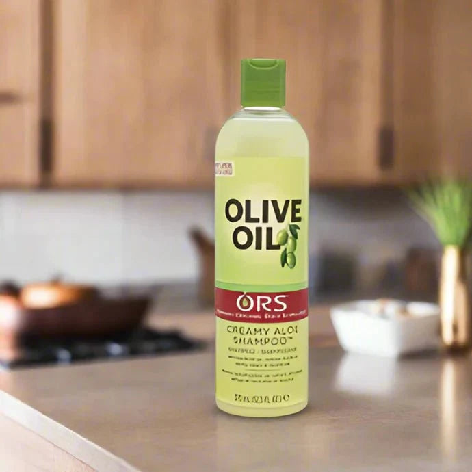 ORS Olive Creamy Aloe Shampoo in 12.5 oz bottle, featuring a white bottle with green and blue accents and a pump dispenser.